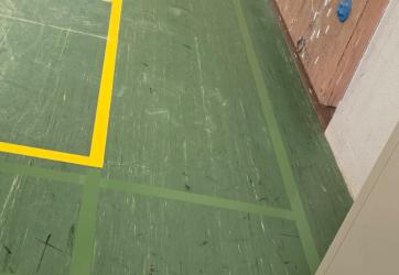 effaçage d'un terrain de badminton par application d'une peinture de couleur identique que le sol