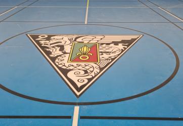 Traçage d'un logo en peinture dans le rond central d'un terrain de basketball