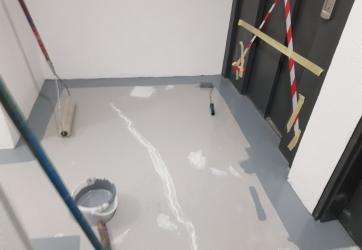 Peinture de sol en cours de réalisation : 1ier couche gris clair, réparations des fissures en blanc, couche de finition gris foncé en cours