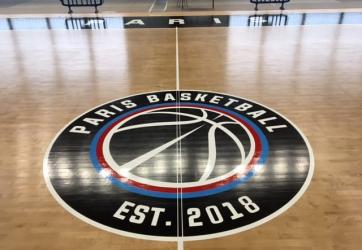 Traçage du logo Paris Basket ball en peinture sur sol Parquet.