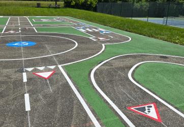 Marquage au sol d'une piste pour apprendre à rouler. coloration en vert des espaces vert, marquages de panneaux de signalisation. chantier sur Ornex dans l'Ain (01)